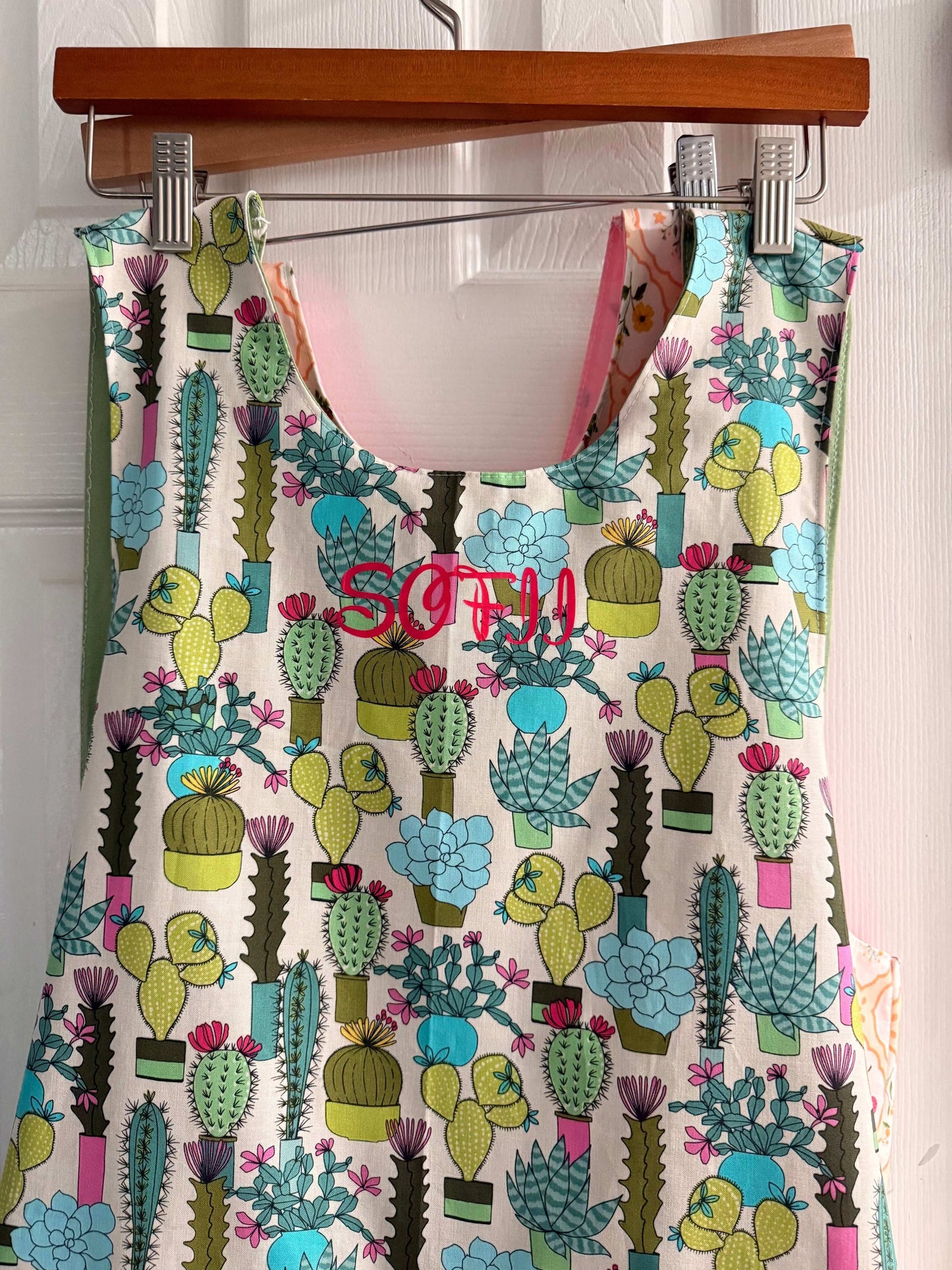 Desert Bloom cross-back apron with vibrant desert bloom pattern and front pockets